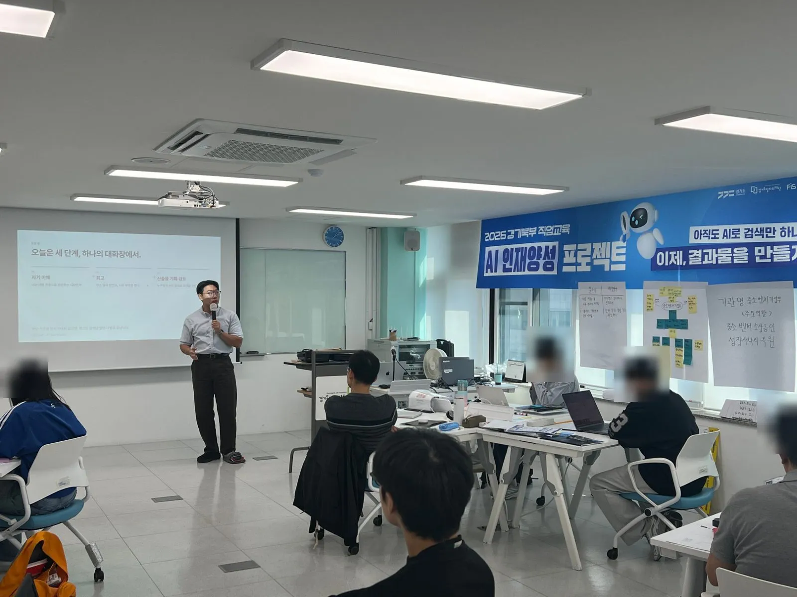 AI 인재양성 프로젝트 현수막 아래에서 세 단계를 설명하는 모습